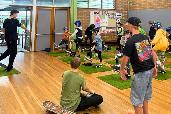 Children learning skateboarding with instructors in a community hall